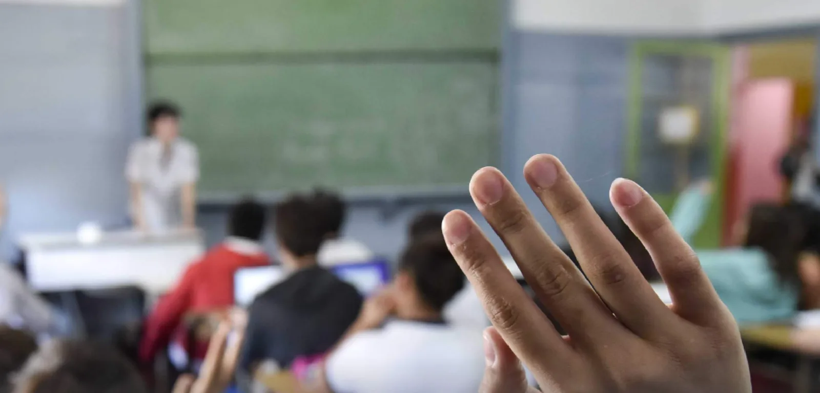 Aula de escuela con alumnos levantando la mano